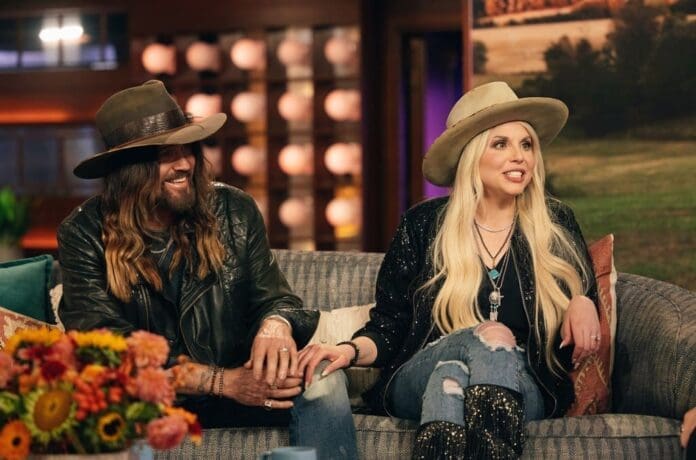 Two people wearing cowboy hats sitting on a couch.