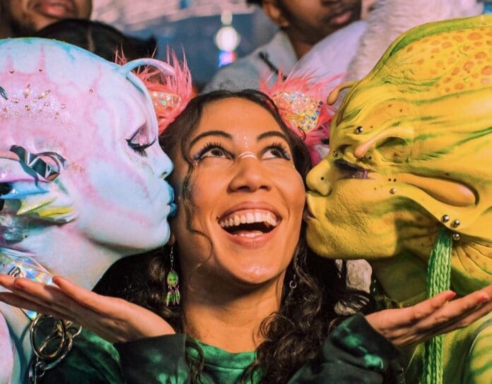 A woman dressed as an alien kisses another woman, creating a beloved and memorable moment.