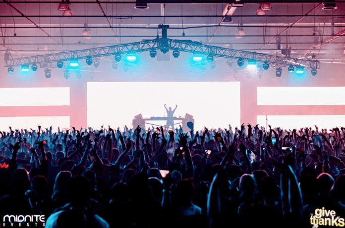 A crowd at a concert with people raising their hands during Give Thanks Returns.