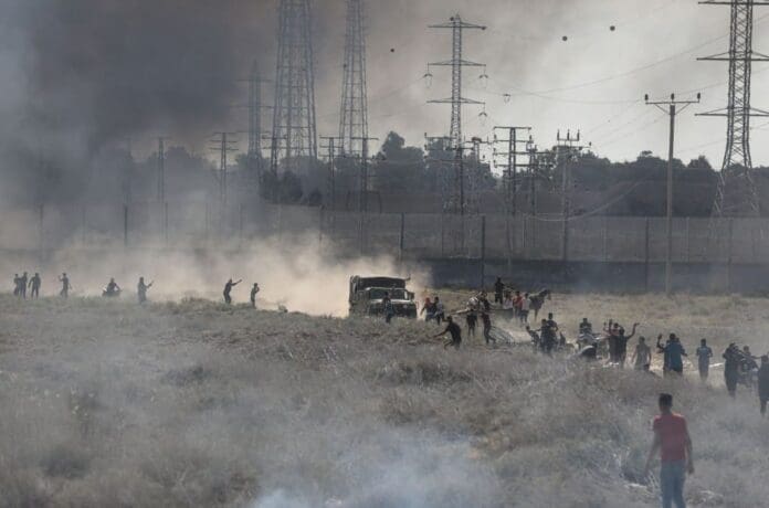 Group of people walking through a field with smoke coming out of it at an Israeli festival.