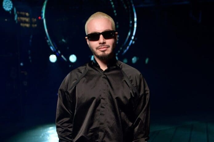 A man in a black shirt standing in front of a circular light.