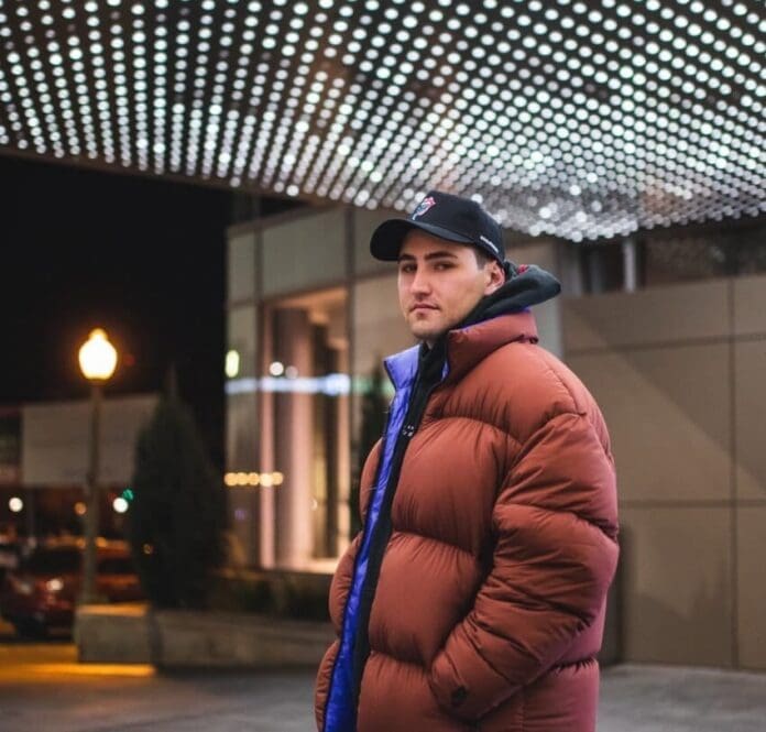 A man in a puffer jacket standing in front of a building at night during Jauz's Wise and Wicked Tour.