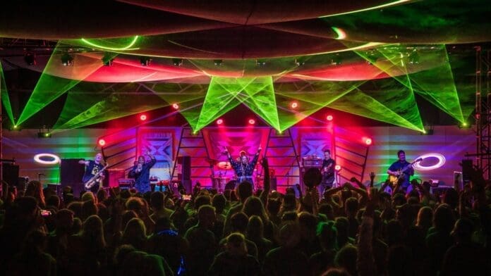 A group of people on stage at a concert with colorful lights, Joshua Tree Music Festival.