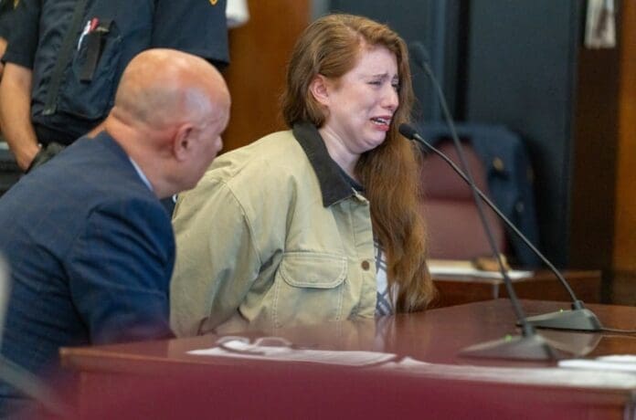 A woman is sitting in a courtroom with a man for fatally shoving a Broadway coach.