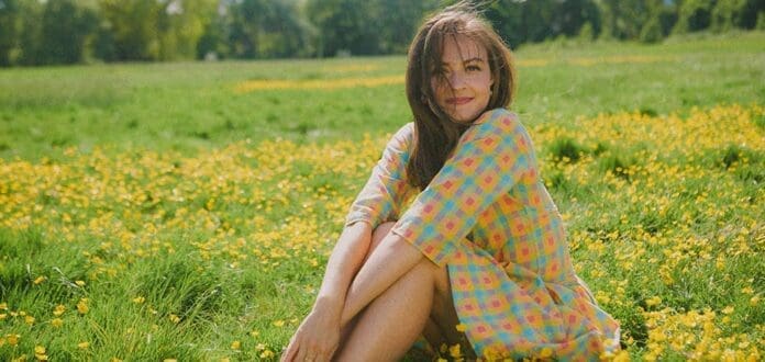 A woman sitting in a field of yellow flowers is the backdrop for songwriter Monica Aben's nostalgic new single 