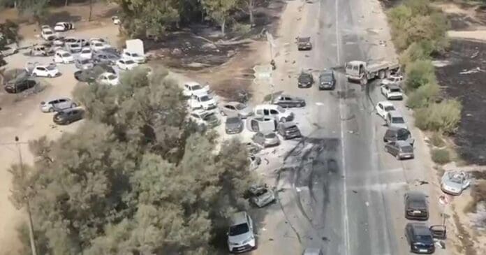 Aerial view of a burned out car on a road following an attack.