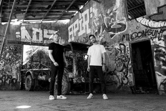 Alex Sonata and TheRio standing in front of a graffiti covered truck.