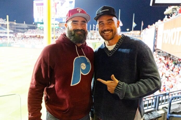 Travis Kelce and Jason posing for a photo at a baseball game.