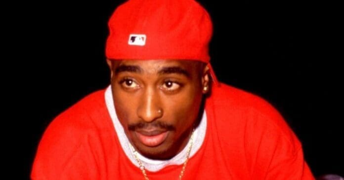 Duane Davis, a suspect in Tupac's murder, wearing a red shirt and holding a microphone.