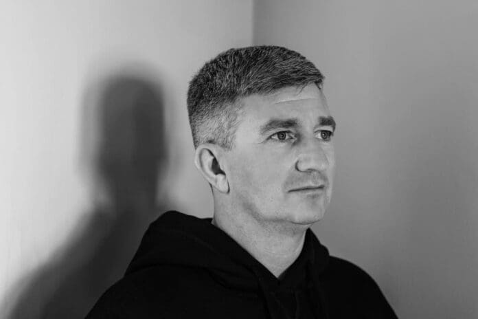 A black and white photo of a man in a black hoodie attending Sunday School.