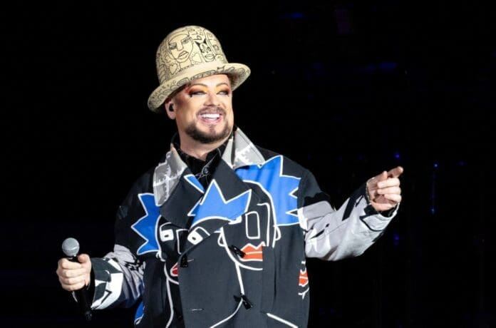 Boy George is holding a microphone.