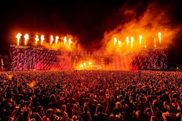 A large crowd at an indoor concert with flames in the background at Creamfields 2024.