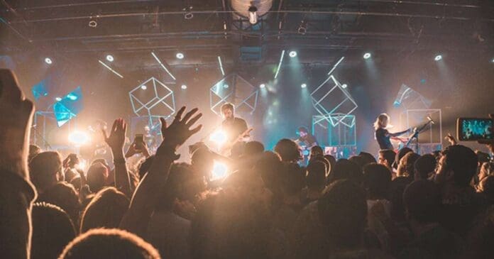 A crowd of musicians at a concert with their hands raised, capturing new data on discrimination.