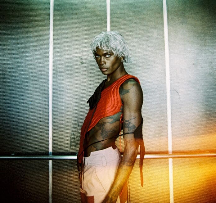 A thought-provoking man with white hair standing in a hallway.