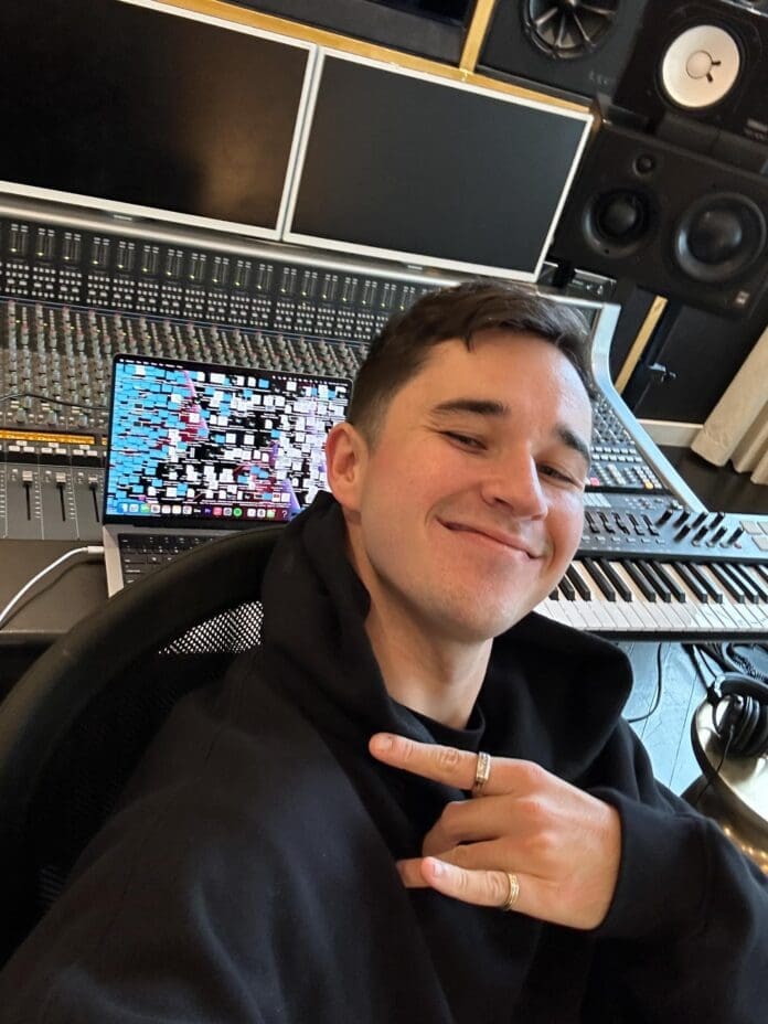 John Summit, wearing a black hoodie, sits confidently in front of a mixing desk while working on his latest album for his upcoming Vegas residency.