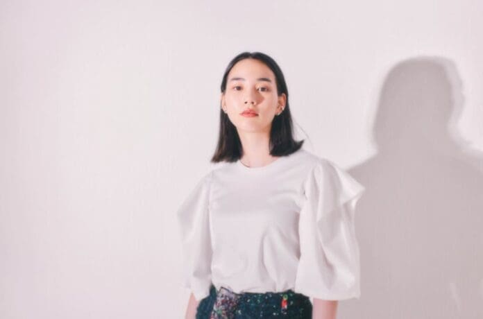 A woman wearing a white top and floral pants is featured in a non-billboard interview for Japan Women in Music.