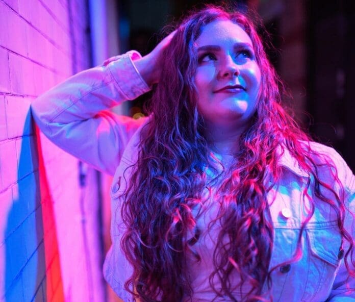 Marcia, the R&B singer, with long curly hair leaning against a wall as she promotes her new single.