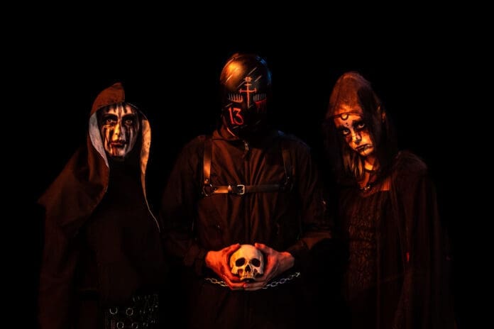 A nightmare-like live experience with a group of people dressed in black and holding a skull.