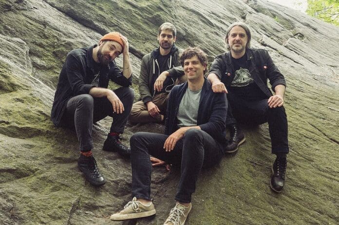 A group of men sitting on top of a large rock, captured in stunning visuals that showcase their camaraderie and embody the spirit of Ultra Major.