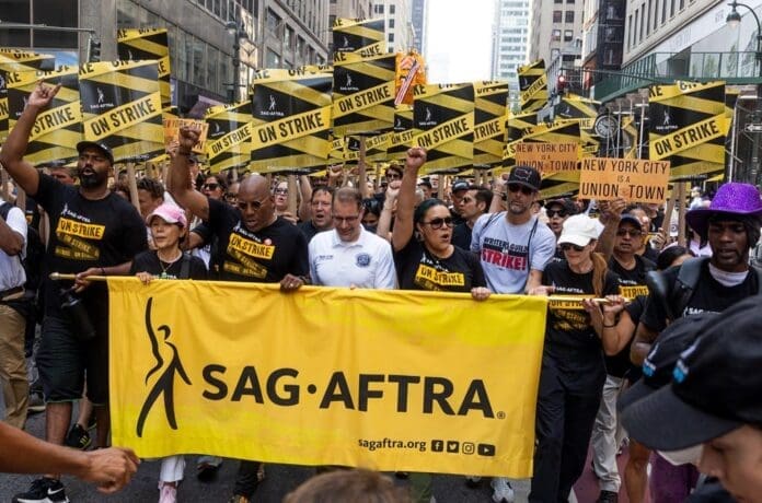 A group of actors holding a banner that says SAG-AFTRA during a strike in Hollywood.