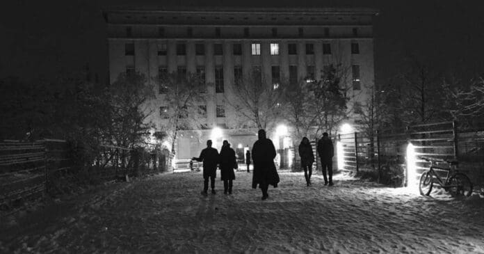 A group of people walking down a snowy path at night.