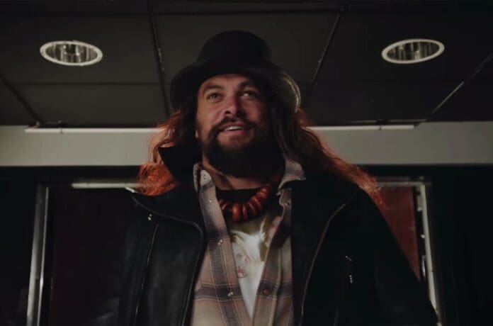 A Jason Momoa look-alike in a leather jacket and hat.