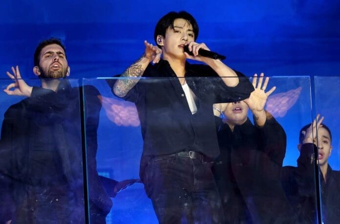 Jung Kook and his group of men surprise Times Square with a mesmerizing performance in front of a glass wall.