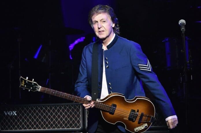 Paul McCartney, a member of the Beatles, plays a guitar on stage during his performance.