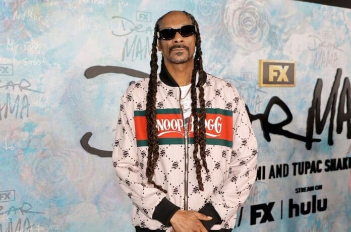 Snoop Dogg poses for a photo at the premiere of 'Dancing with the Stars' while carrying a list of items.